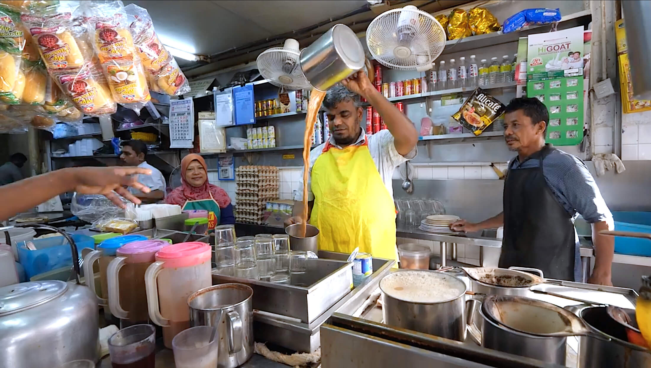 The owner pouring milk tea from heating vessel to glass is what makes the Teh Tarik so frothy and foamy